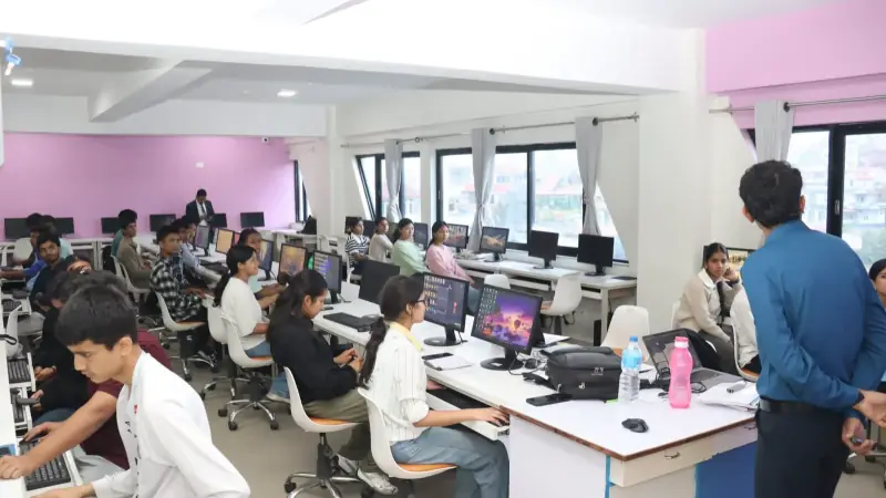 A wide computer lab at Triton SS & College, rows of students at desktop machines with an instructor standing at the right.